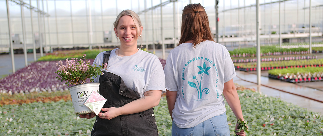 Woman wearing the Great Garden Plants t shirt overlooking the greenhouse