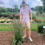 Man standing in a garden wearing a patterned shirt and sunglasses